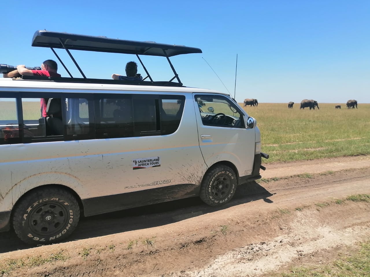 Our safari van with background of a herd of elephants in Amboseli